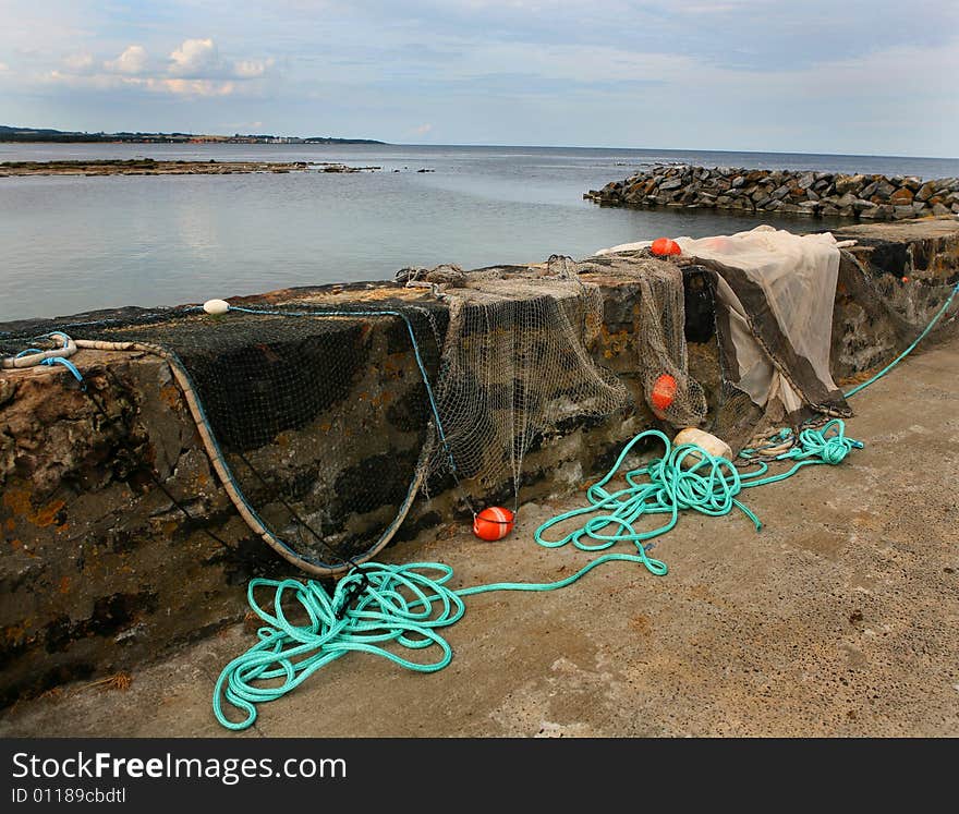 Fishing nets with floats drying on a wall in the harbour. Fishing nets with floats drying on a wall in the harbour