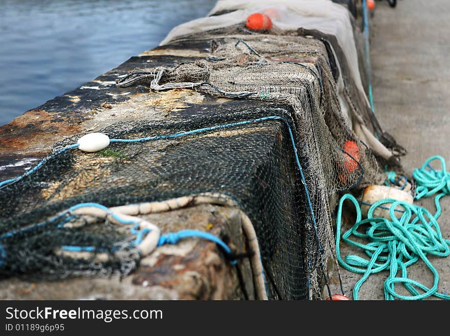 Fishing nets with floats drying on a wall in the harbour. Fishing nets with floats drying on a wall in the harbour