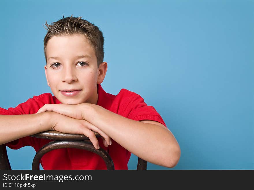 A pensive youngster sitting in an old bentwood back chair.(copy space, blue screen). A pensive youngster sitting in an old bentwood back chair.(copy space, blue screen)