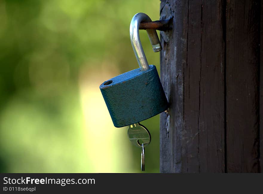 Padlock with a key hanging on a wooden barn