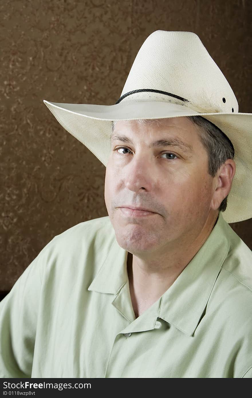 Man wearing a white cowboy hat in front of a gold background. Man wearing a white cowboy hat in front of a gold background