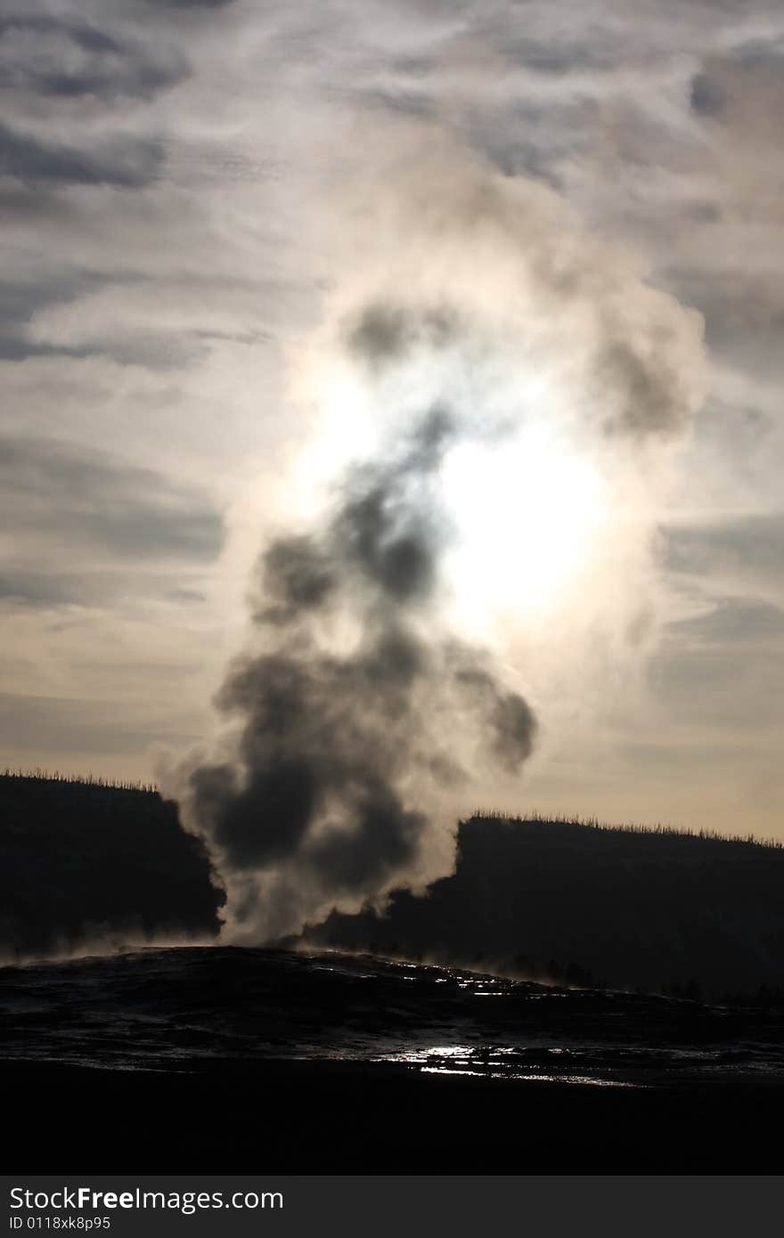 Old Faithful Geyser silhouetted at sunset - Yellowstone National Park. Old Faithful Geyser silhouetted at sunset - Yellowstone National Park.