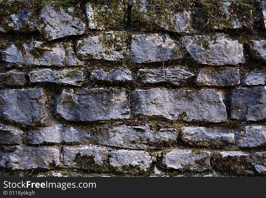 Old stones wall covered with moss and vegetation