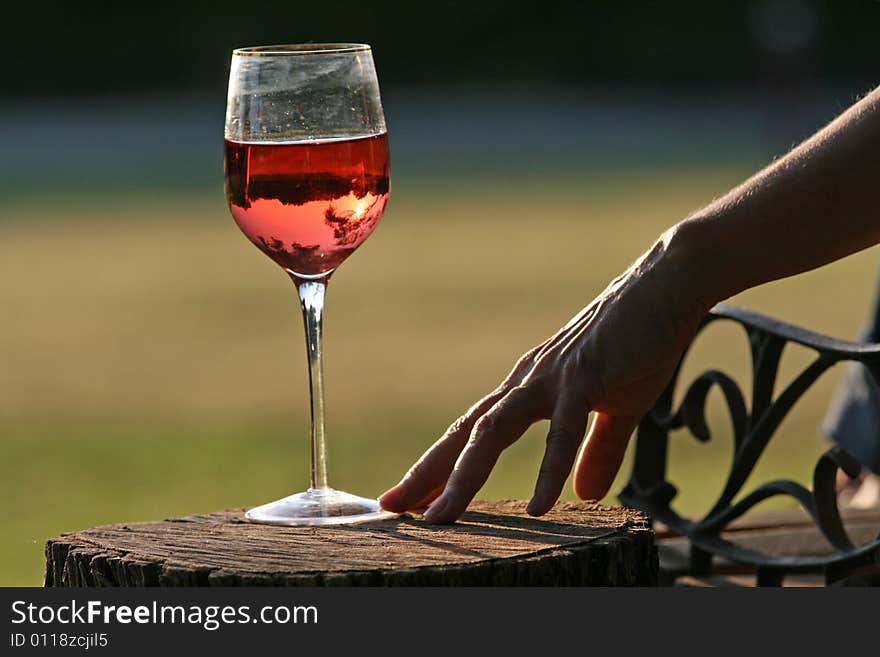 Woman reaches for glass of wine at sunset overlooking country. Woman reaches for glass of wine at sunset overlooking country.