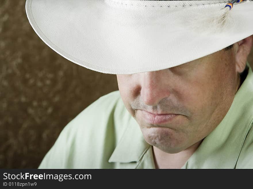 Man beneath a white cowboy hat in front of a gold background. Man beneath a white cowboy hat in front of a gold background