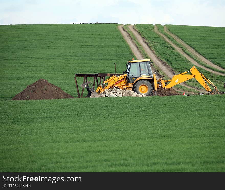 Excavator in the green field