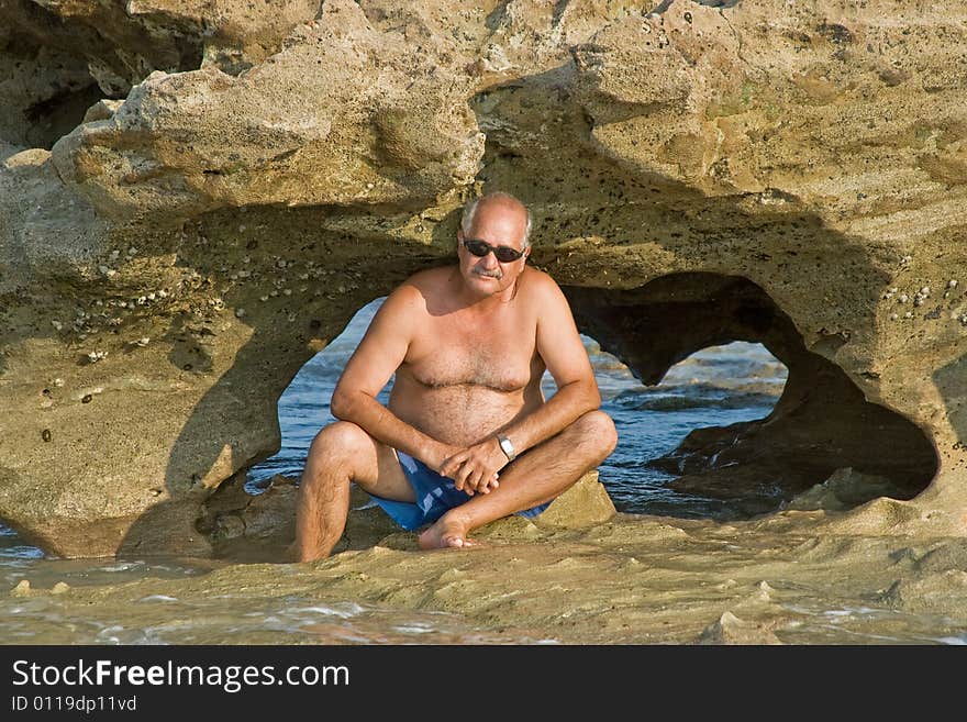 An arch is revealed at low tide with senior man in foreground in Coral Reef Park, Florida. An arch is revealed at low tide with senior man in foreground in Coral Reef Park, Florida.