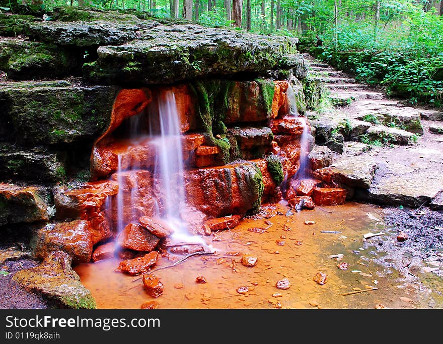 This is a shot of a small waterfall. There is a lot of green, rock steps and ever so small a cliff in this image. The spring is called Yellow Spring. This is a shot of a small waterfall. There is a lot of green, rock steps and ever so small a cliff in this image. The spring is called Yellow Spring.