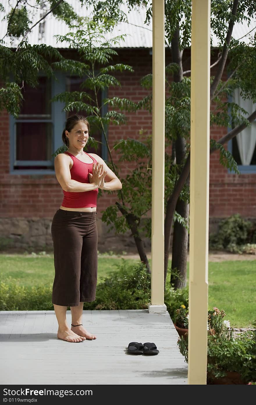 Pretty Young Woman doing Yoga on a Porch Looking Towards the Camera. Pretty Young Woman doing Yoga on a Porch Looking Towards the Camera