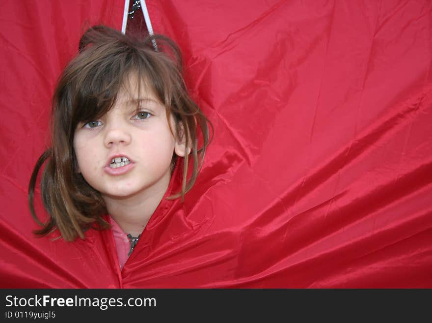 Young girl looking out of a red tent. Young girl looking out of a red tent.