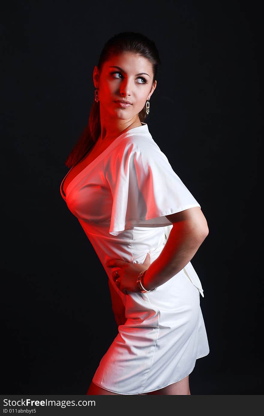 A young beautiful girl is dressed in white clothes at black background. A young beautiful girl is dressed in white clothes at black background