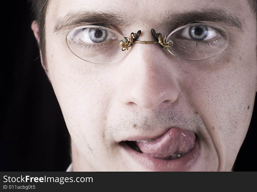 Face of young man in glasses on a black background