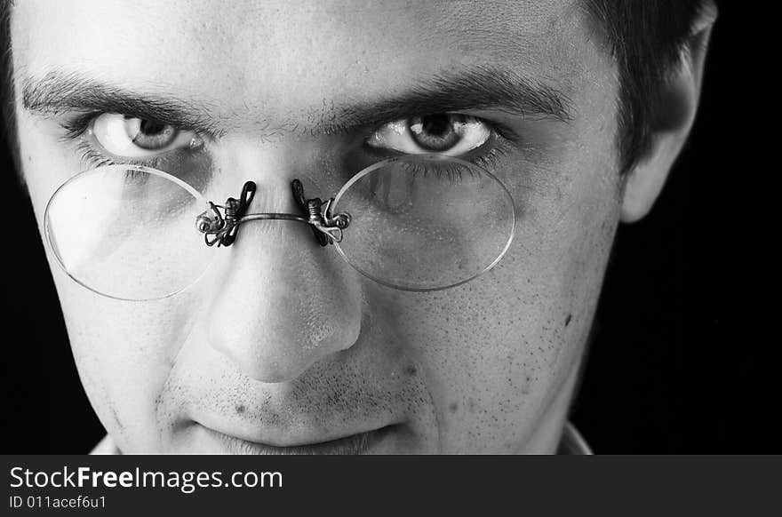 Face of young man in glasses on a black background