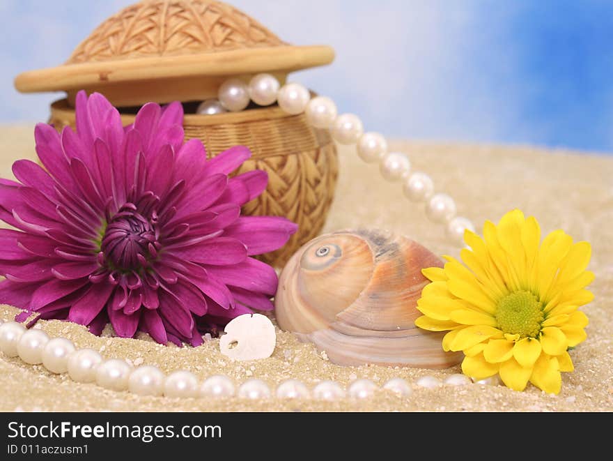 Flowers and Jewelry on Sand With Blue Background