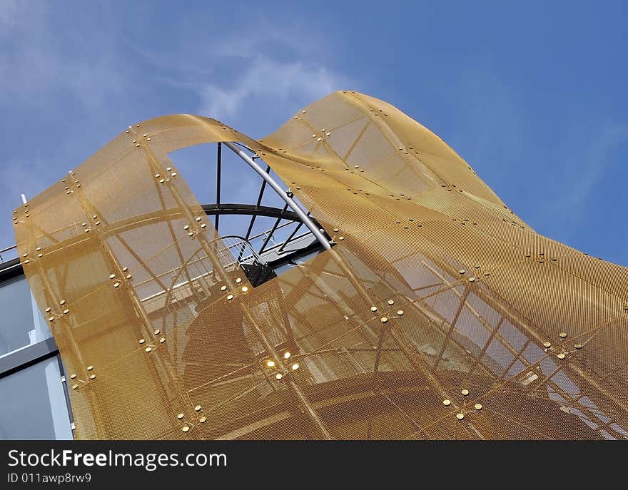 A part of modern building with golden net against blue sky. Den Haag, Holland. A part of modern building with golden net against blue sky. Den Haag, Holland