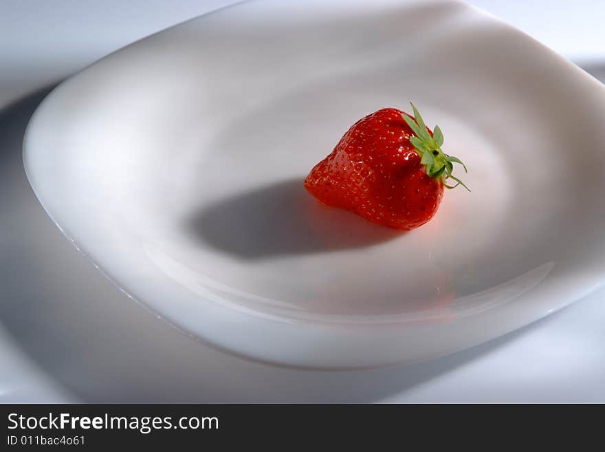 One strawberry on white plate