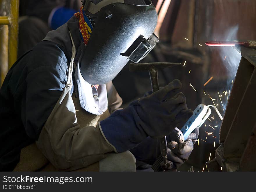 Welder with heavy protective clothing working on a steel construction. Welder with heavy protective clothing working on a steel construction.