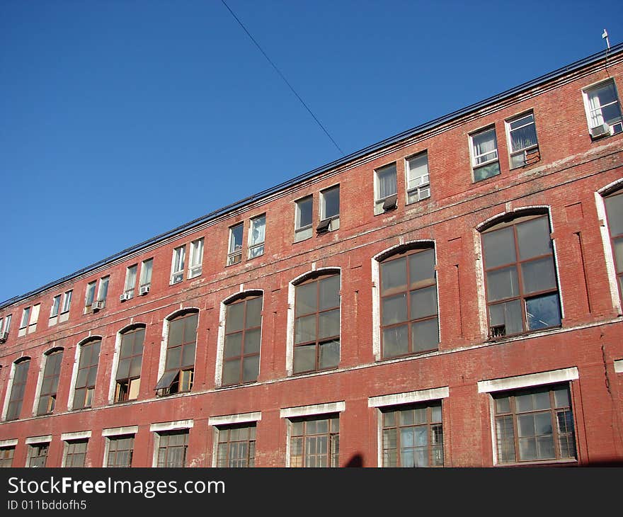 The old thrown Factory from a red brick greater glass windows on a background of the dark blue sky. The old thrown Factory from a red brick greater glass windows on a background of the dark blue sky