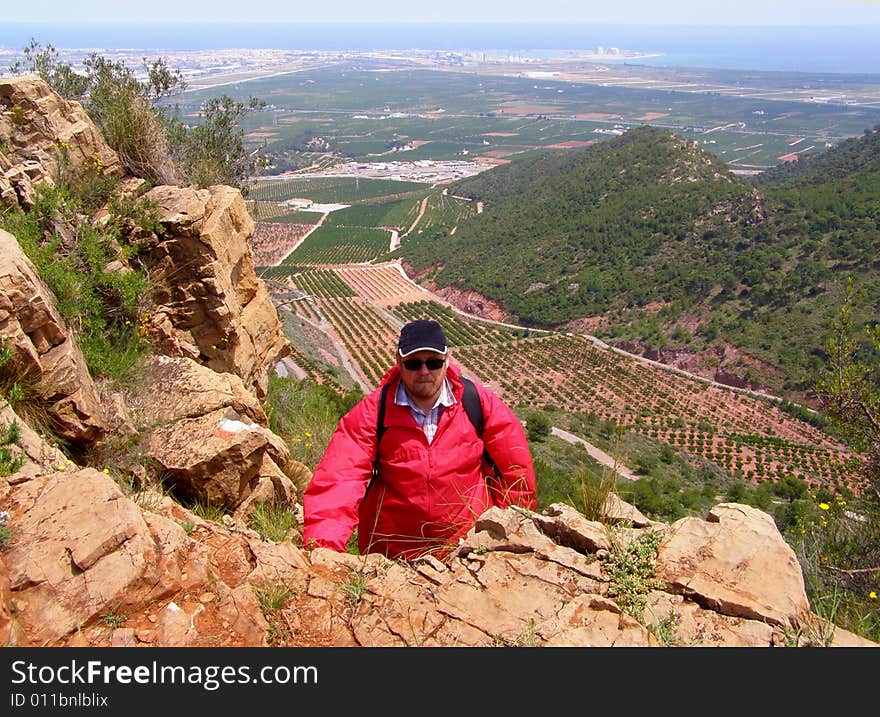 The man in red jacket in small mountains near the see. The man in red jacket in small mountains near the see