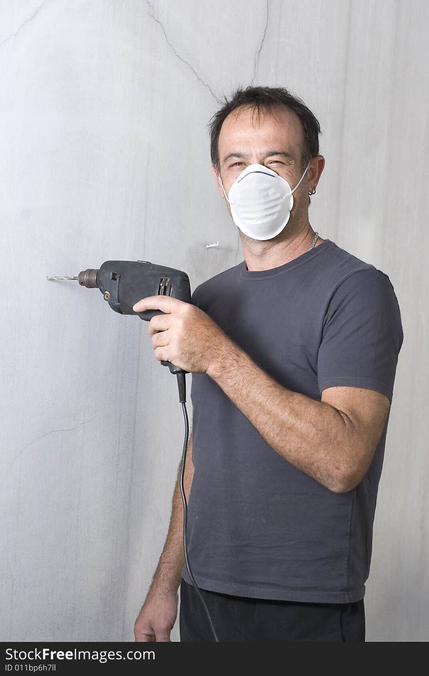 Man standing with mask holding drill and looking at camera. Vertically framed photo. Man standing with mask holding drill and looking at camera. Vertically framed photo