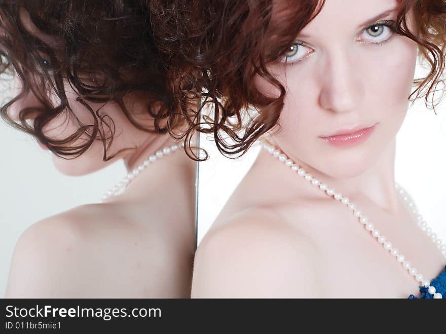 Young girl in a dark blue corset and with beads on a neck - in earnest looks in a shot, leaning one's elbows on a mirror in which reflected. Young girl in a dark blue corset and with beads on a neck - in earnest looks in a shot, leaning one's elbows on a mirror in which reflected