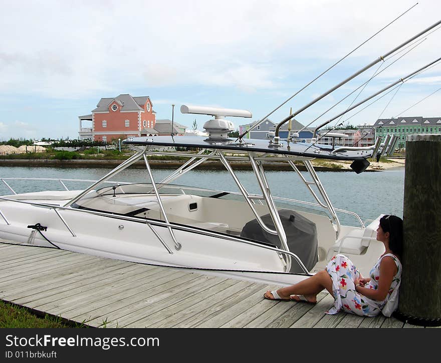 The girl sitting by the boat in Sandyport harbour (Nassau, The Bahamas). The girl sitting by the boat in Sandyport harbour (Nassau, The Bahamas).