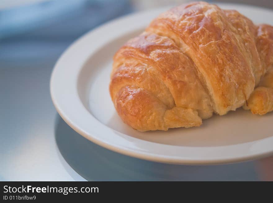 A gourmet fresh baked croissant, bathed in cool, elegant light. A gourmet fresh baked croissant, bathed in cool, elegant light.