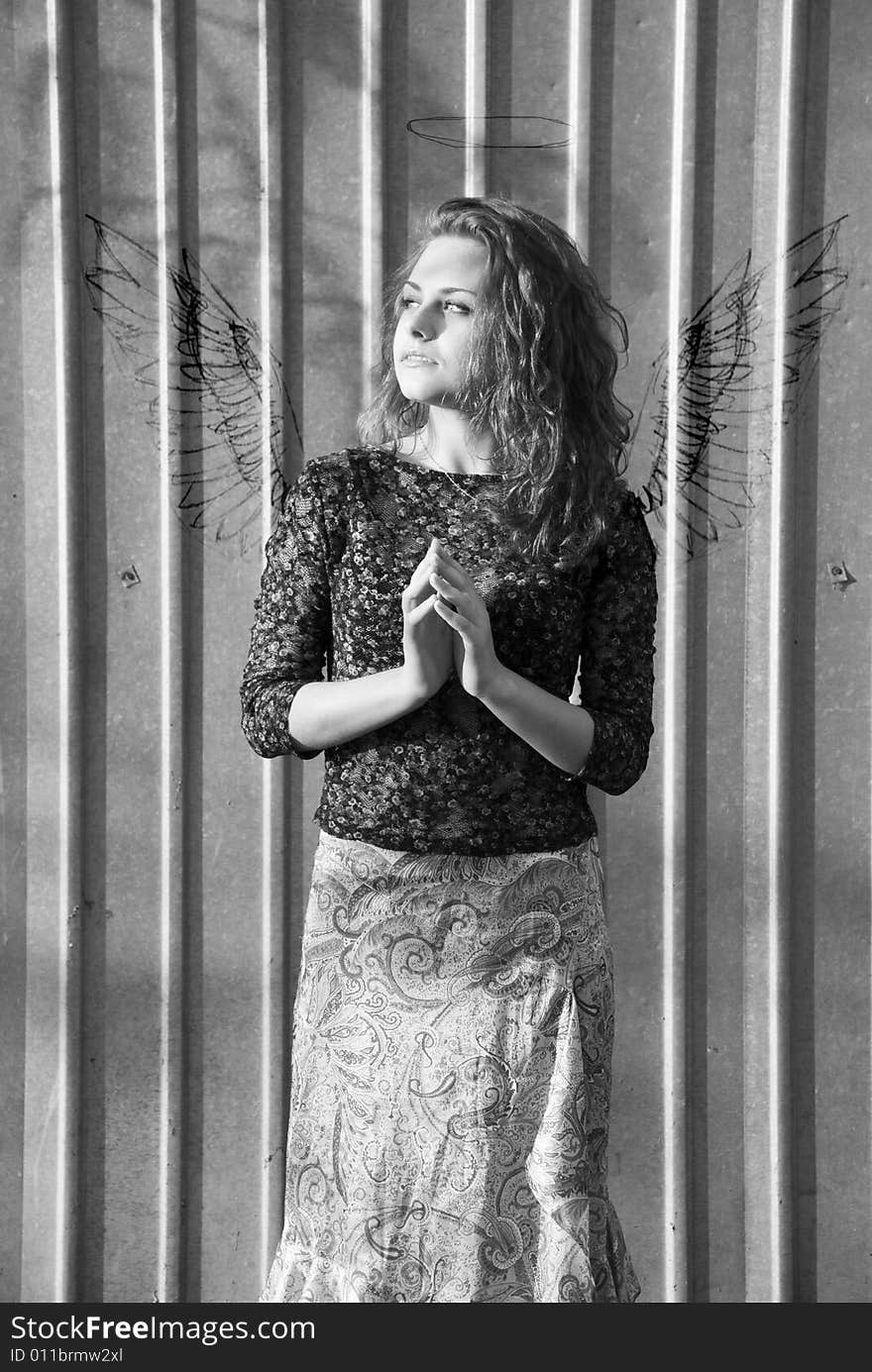 Photo of girl standing near a fence, with the wings and nimbus drawn on a fence. Photo of girl standing near a fence, with the wings and nimbus drawn on a fence