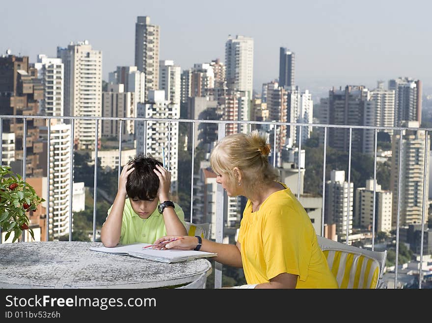 Woman instructing boy while sitting on balcony overlooking city. Horizontally framed photo. Woman instructing boy while sitting on balcony overlooking city. Horizontally framed photo.