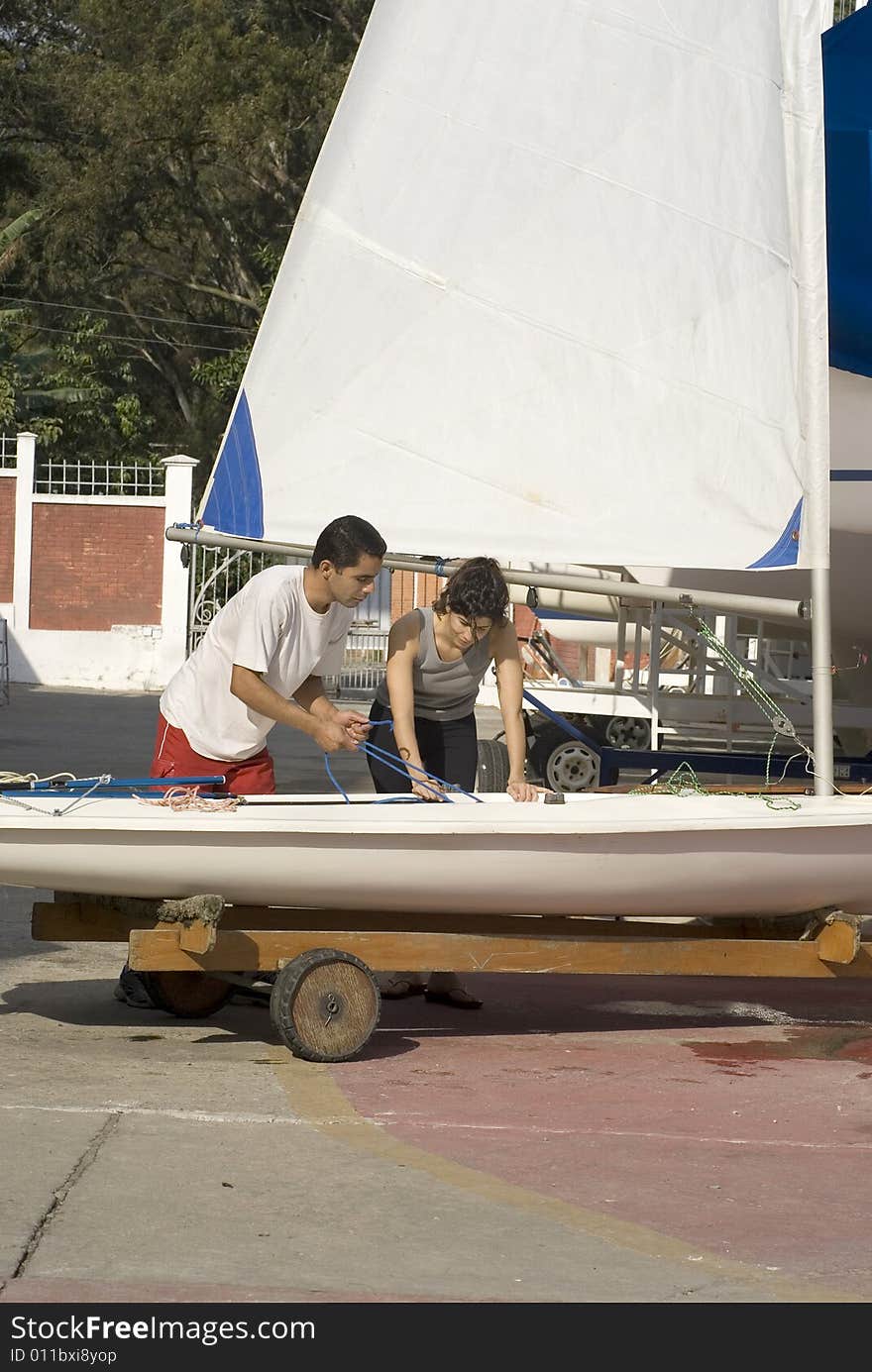 Man and woman setting up sail rigging in preparation to sail. Vertically framed photo. Man and woman setting up sail rigging in preparation to sail. Vertically framed photo