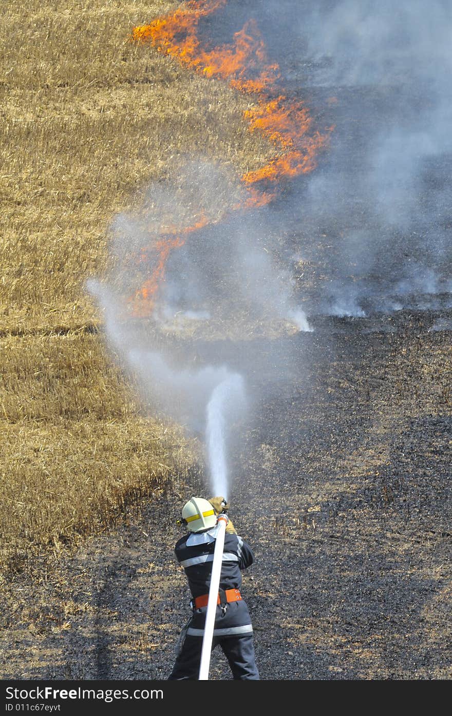 A firefighter extinguish the burning stubble field. A firefighter extinguish the burning stubble field