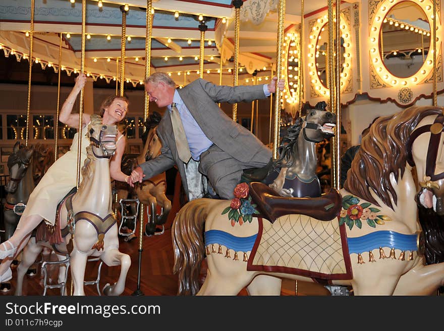 An active mature couple enjoying a merry-go-round together. An active mature couple enjoying a merry-go-round together.