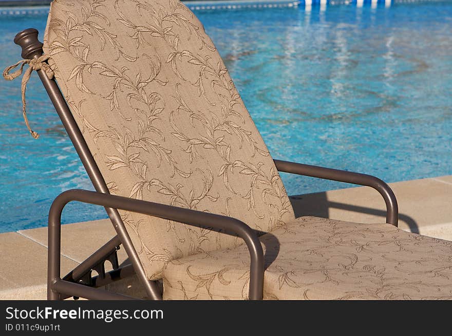 An image of a patio chair next to an aqua blue pool