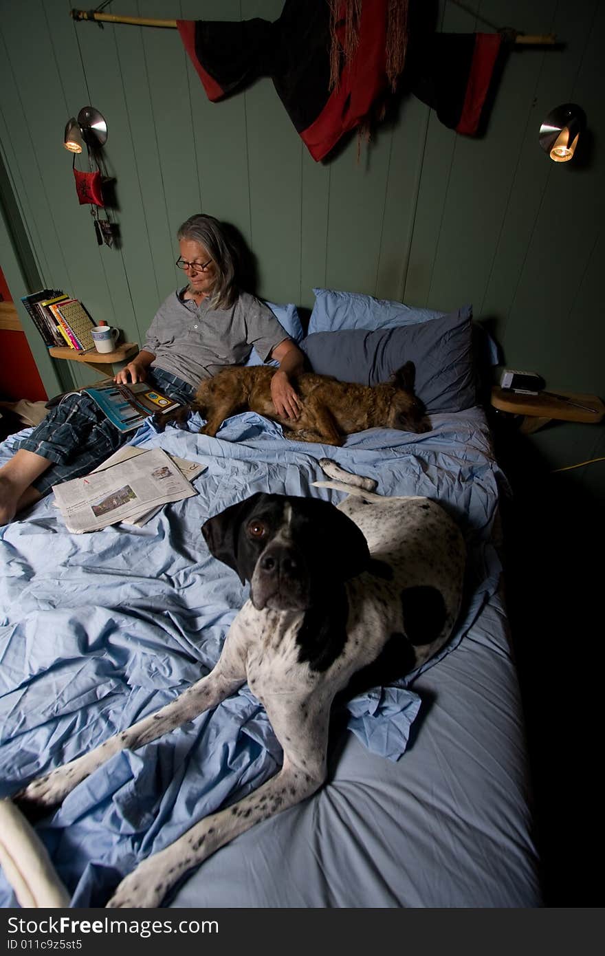 Senior woman in bed reading magazine, with dog. Senior woman in bed reading magazine, with dog