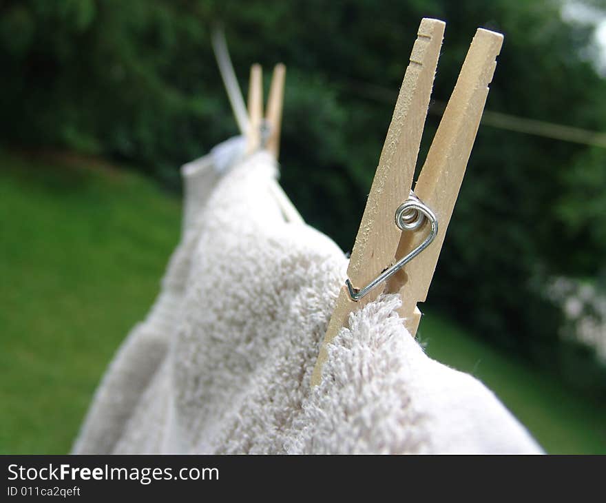 Wooden clothes pins holding towel on clothes line to dry. Wooden clothes pins holding towel on clothes line to dry