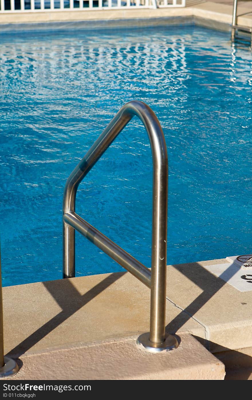 An image of ladder leading into a bright blue pool. An image of ladder leading into a bright blue pool