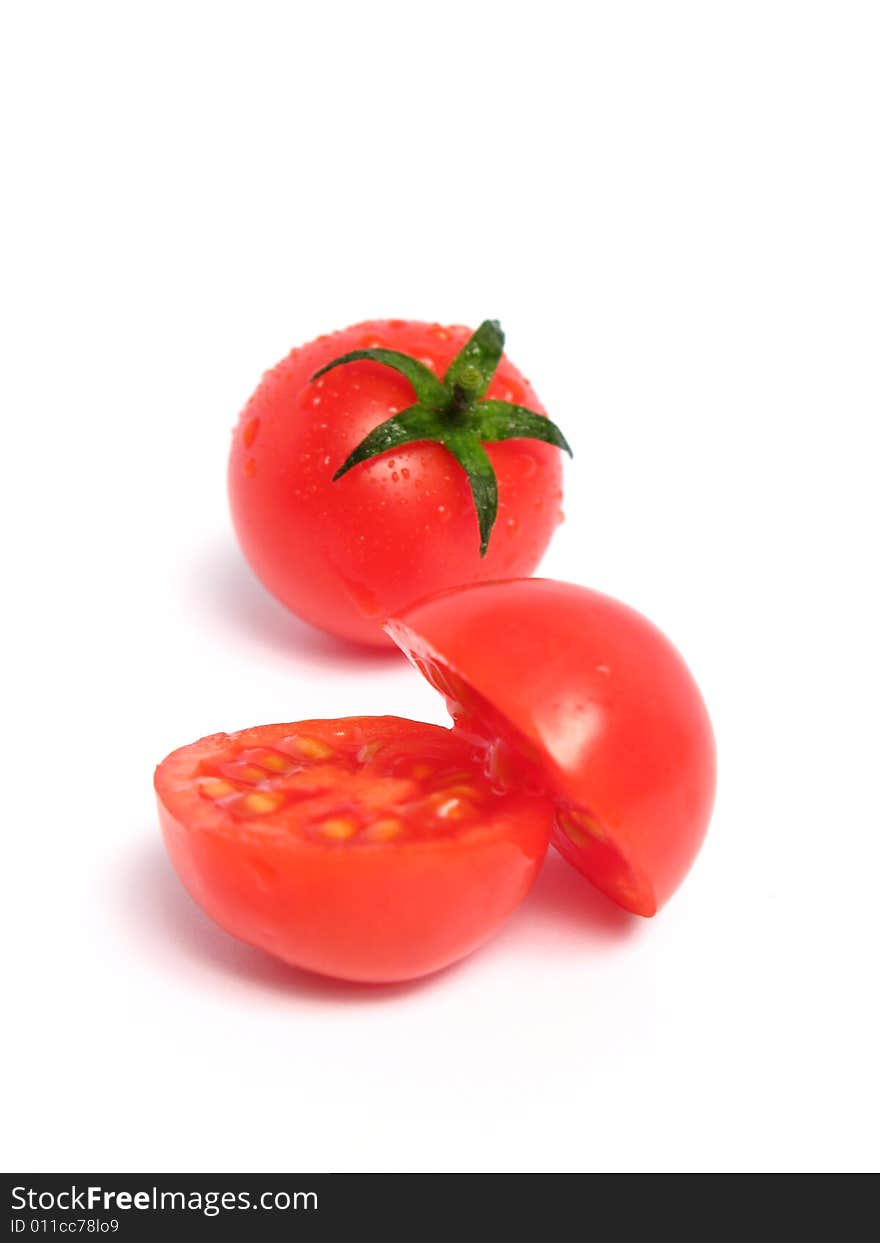 Two cherry tomatoes together and one is cut in the middle, on a white background