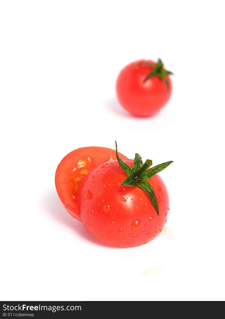 Two cherry tomatoes together and one is cut in the middle, on a white background