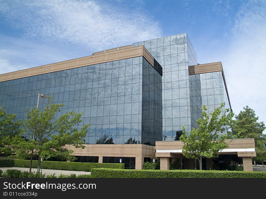 A building with a glass exterior reflecting the sky and clouds above. A building with a glass exterior reflecting the sky and clouds above.