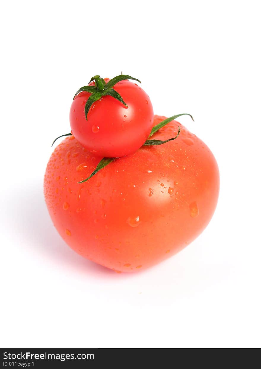 Tomato compared to cherry tomato on white background. Tomato compared to cherry tomato on white background