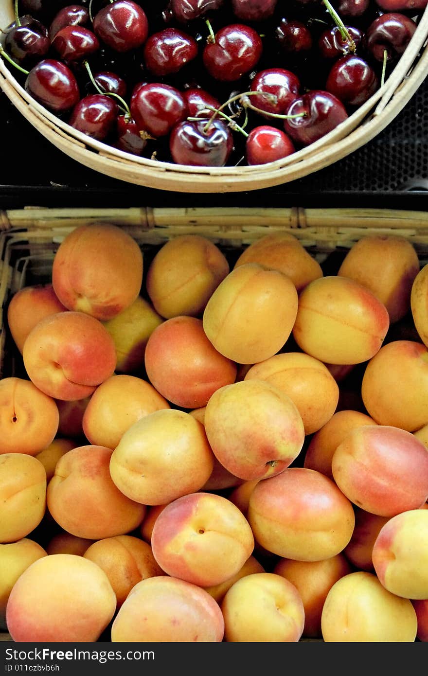 Baskets full of plump peaches and red cherries. Baskets full of plump peaches and red cherries.