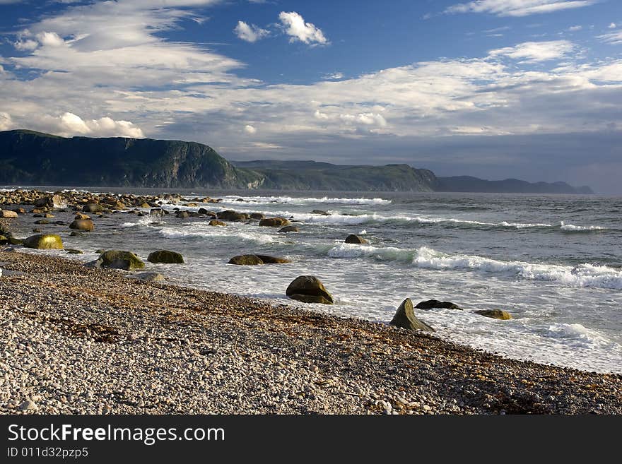 Waves highlighted by late afternoon sun break on a pebble beach. Waves highlighted by late afternoon sun break on a pebble beach