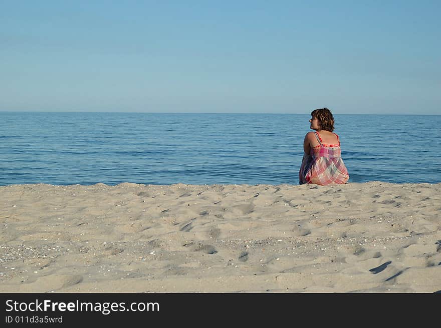 Young woman is sitting on the seashore. Young woman is sitting on the seashore