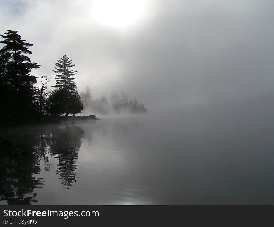 Foggy mist over lake in Adirondacks as the sun rises.