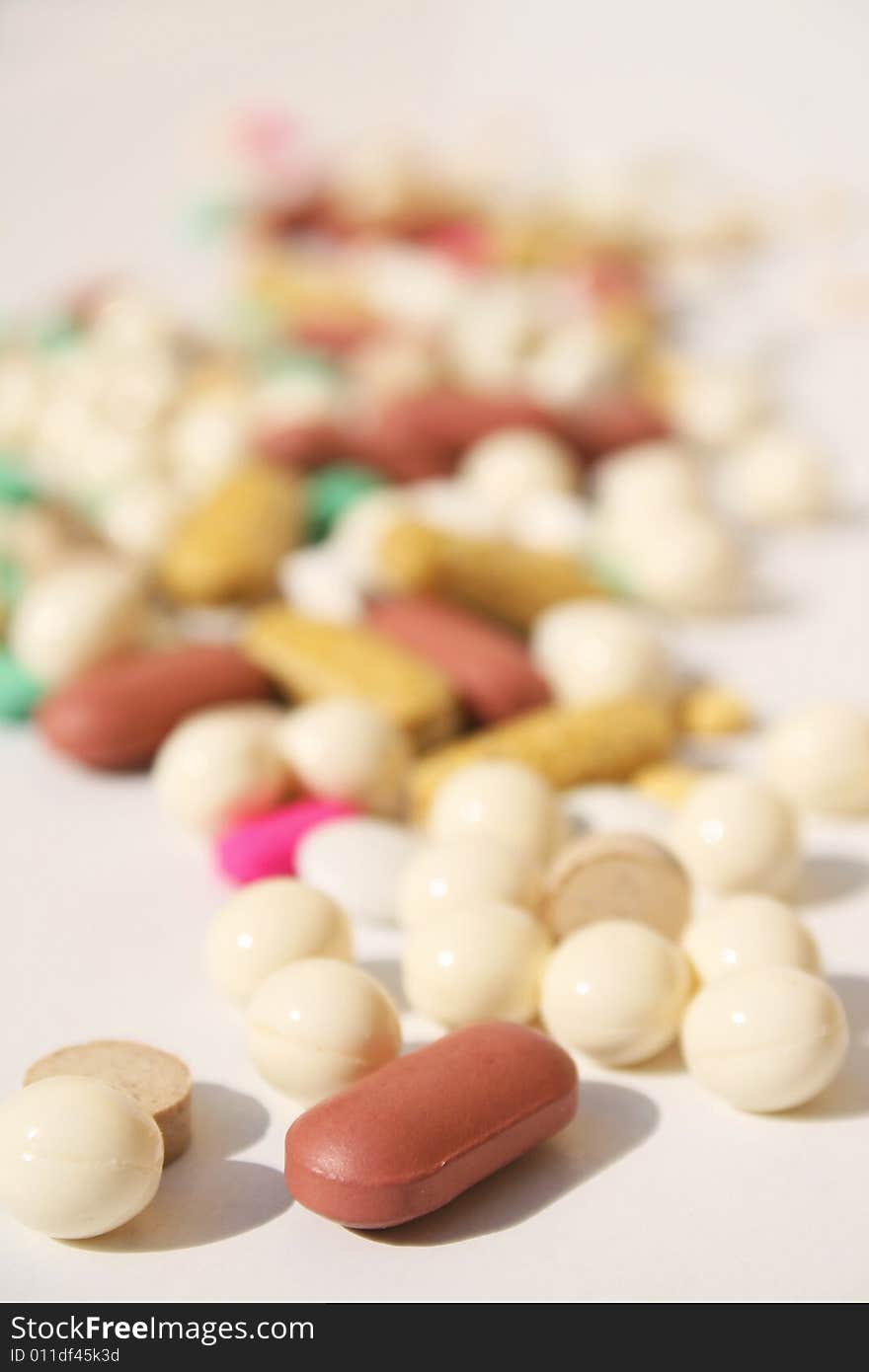 Various pills against white background with shallow depth of field on foreground. Various pills against white background with shallow depth of field on foreground