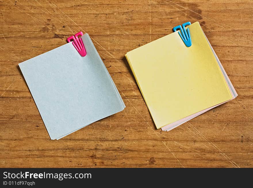 Two Post it with plastic clip on wooden board.