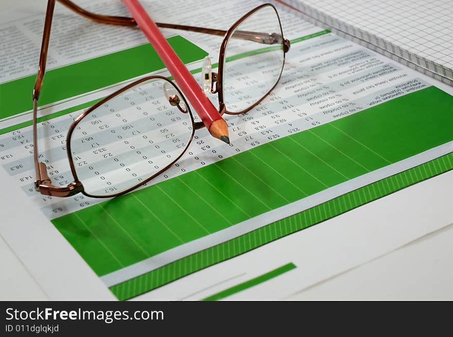 Glasses and red pencil on the table