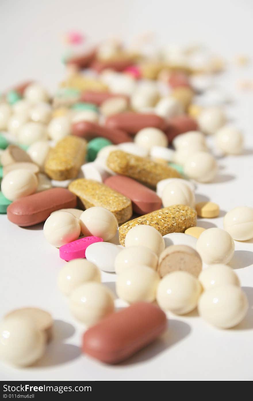 Various pills against white background with shallow depth of field on midground. Various pills against white background with shallow depth of field on midground