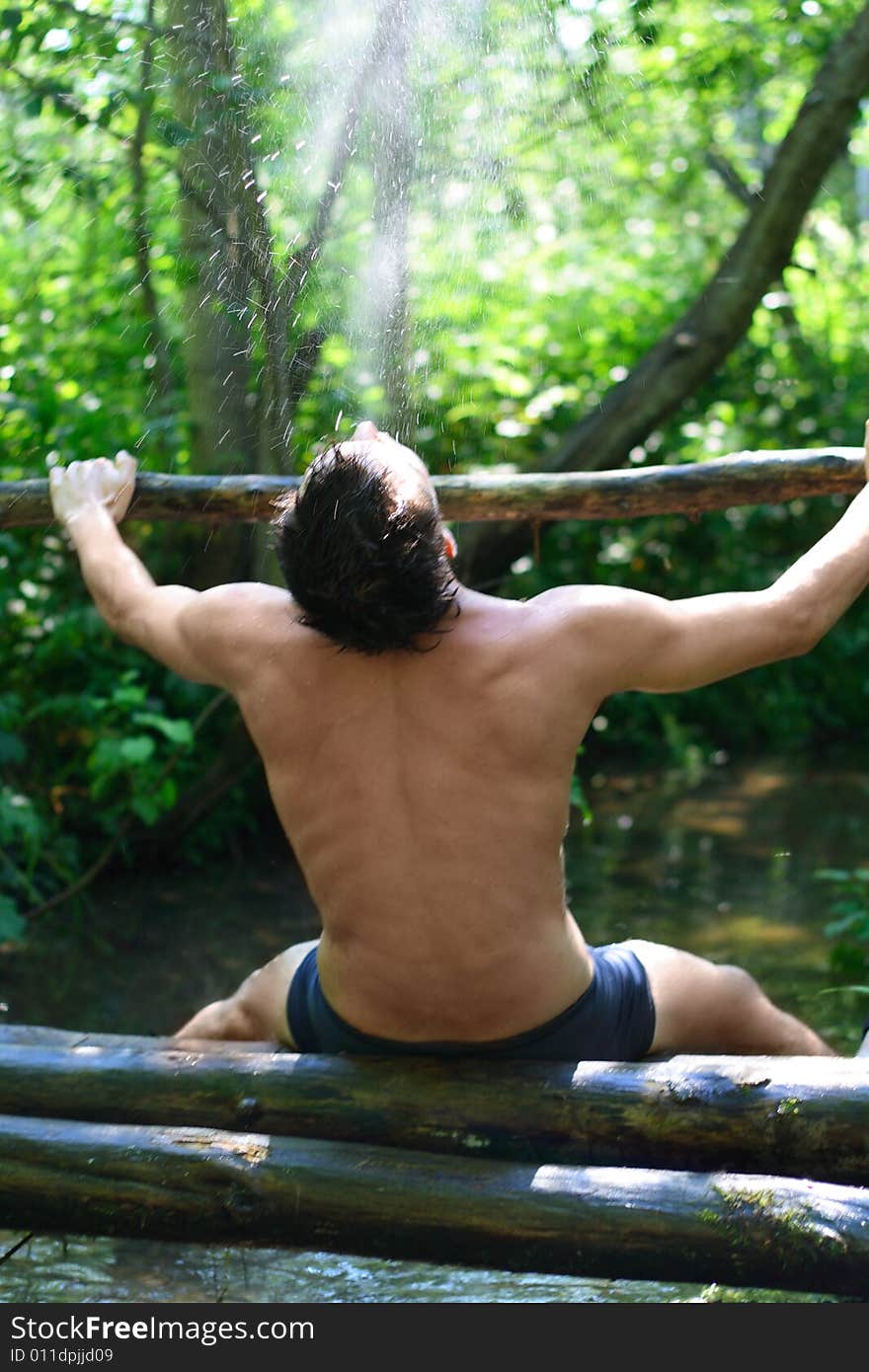 Man is sitting in forest on logs under sunny rain. Man is sitting in forest on logs under sunny rain