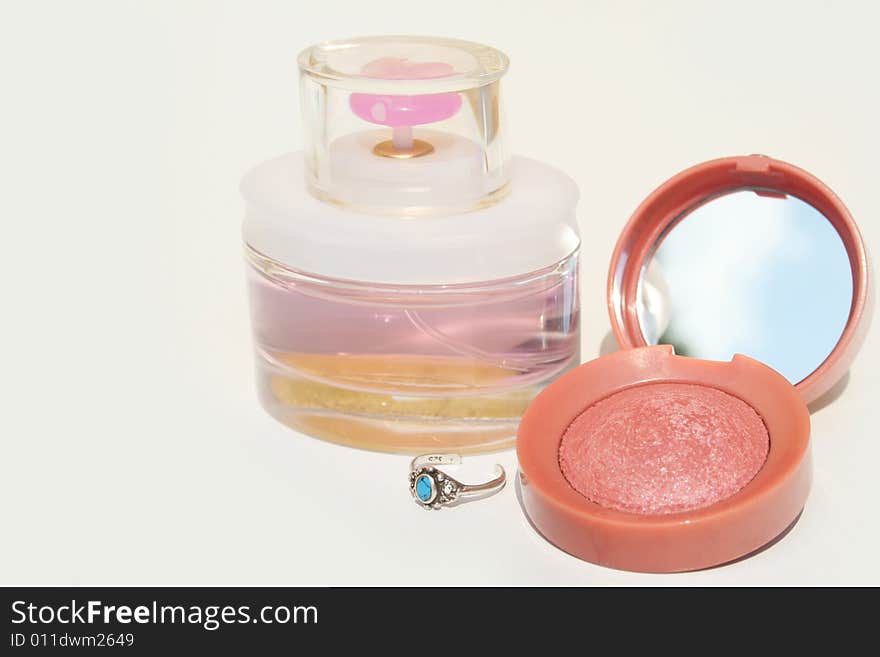 Perfume, blush and a blue stone ring on white background with copy space on left. Perfume, blush and a blue stone ring on white background with copy space on left